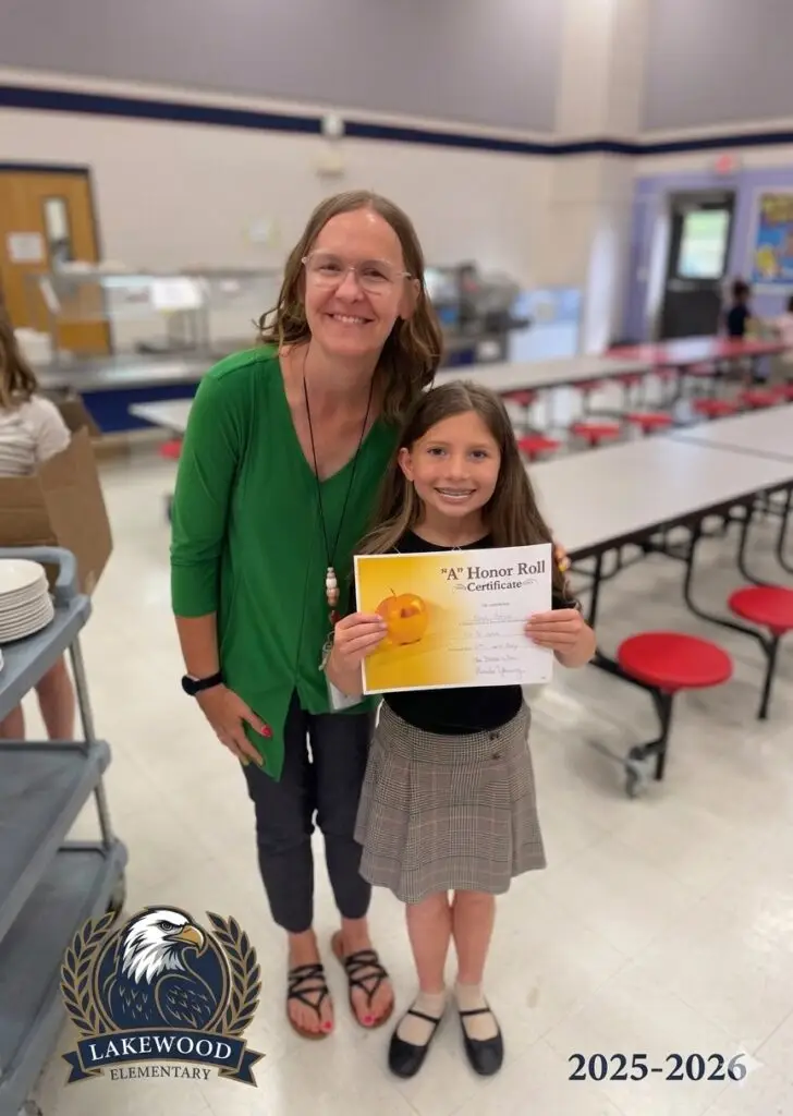 Poppy Mixon with her teacher Ms. Amanda holding her A Honor Roll certificate